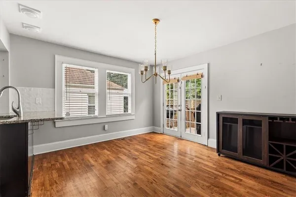 a view of an empty room with a window and kitchen view