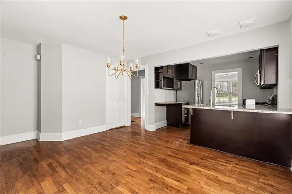 a view of kitchen and empty room with wooden floor