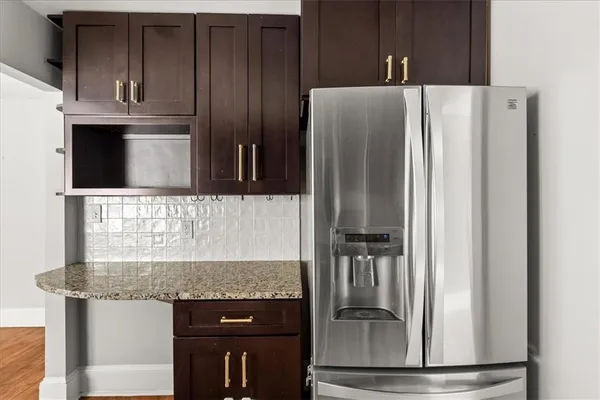 a kitchen with granite countertop a refrigerator and a stove top oven