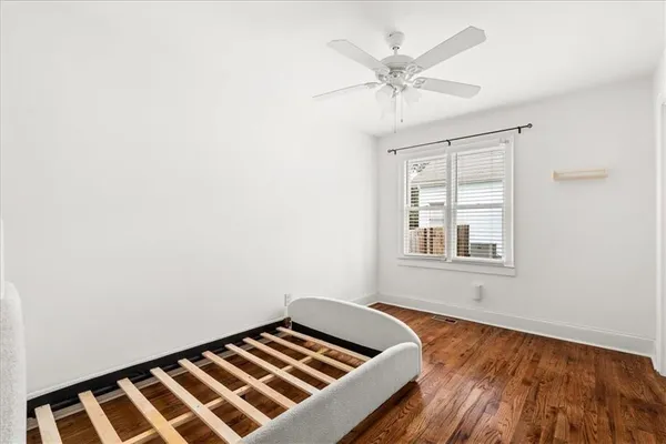 an empty room with wooden floor closet and windows