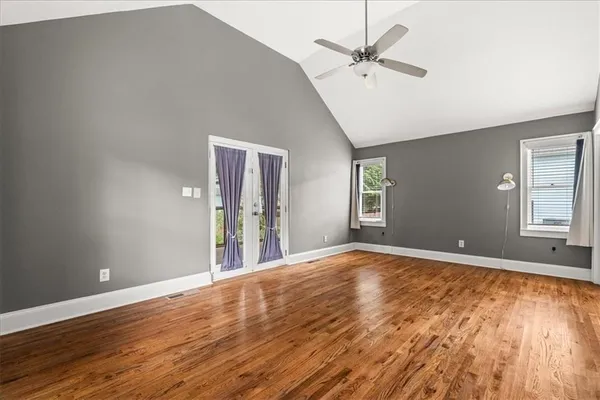 a view of an empty room with window and wooden floor