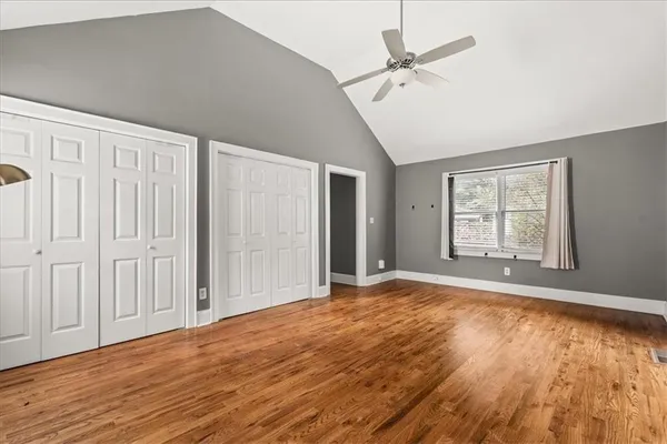 an empty room with wooden floor fan and windows