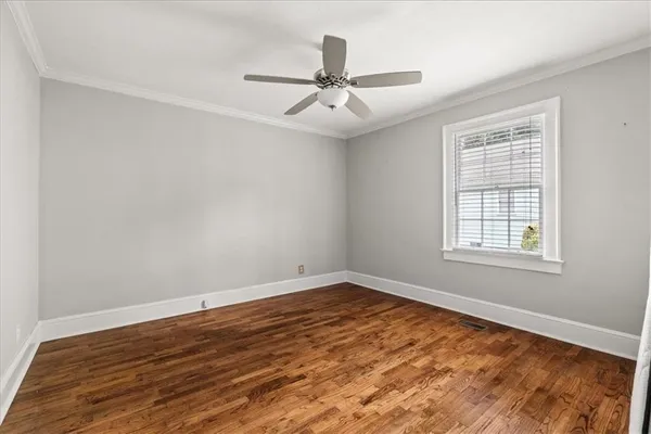 an empty room with wooden floor ceiling fan and windows