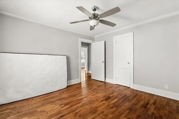an empty room with wooden floor and ceiling fan