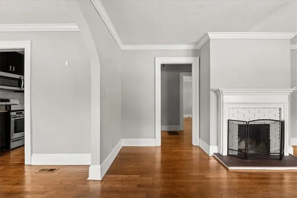 a view of an empty room with wooden floor and a fireplace