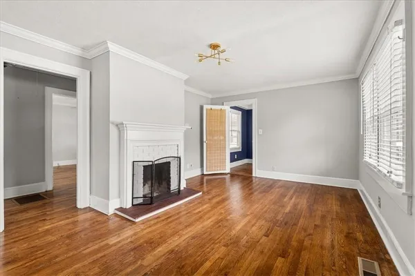 an empty room with wooden floor fireplace and windows