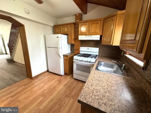 a kitchen with a refrigerator a stove top oven a sink and dishwasher with wooden floor