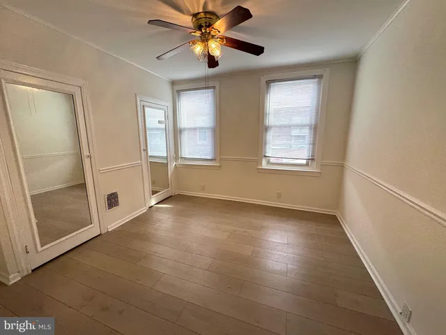 a view of an empty room with a window and a kitchen view