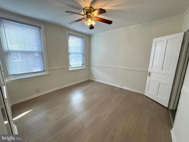 a view of empty room with wooden floor and fan