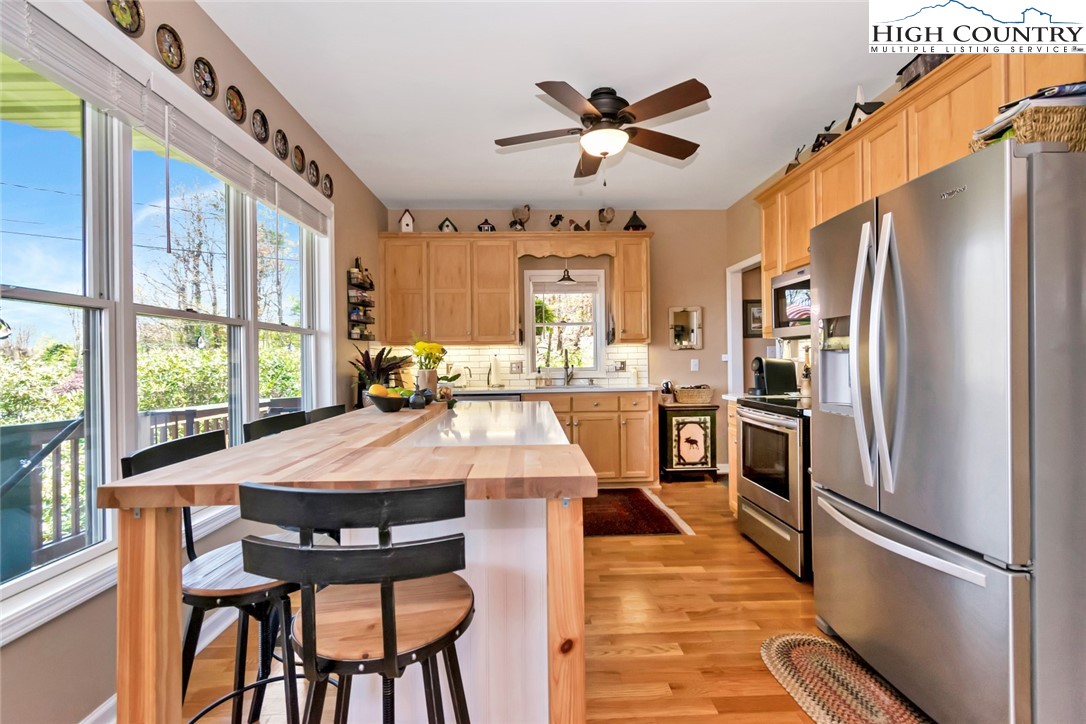 190 Summit Park Circle Boone, NC 28607 - Photo 7 of 50 a kitchen with stainless steel appliances kitchen island granite countertop a refrigerator a stove a microwave oven with a dining table and chairs with wooden floor