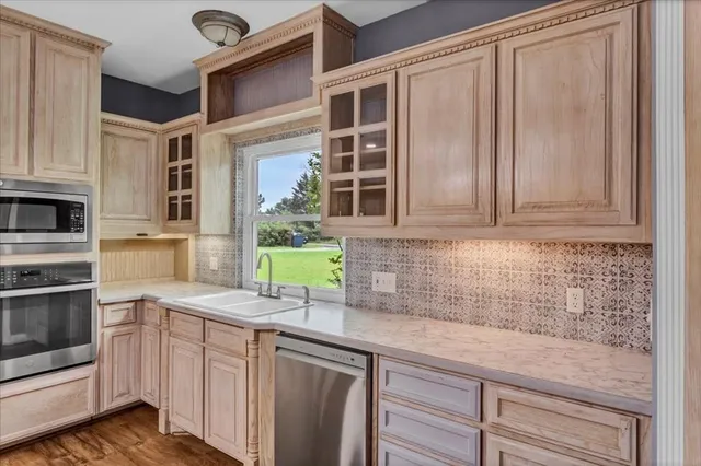 a kitchen with stainless steel appliances granite countertop white cabinets and window