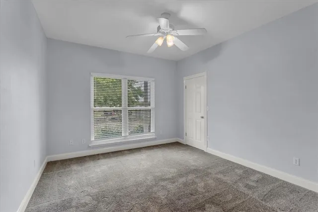 an empty room with a window and a fan