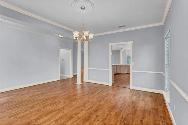 a view of an empty room with wooden floor fridge and a window