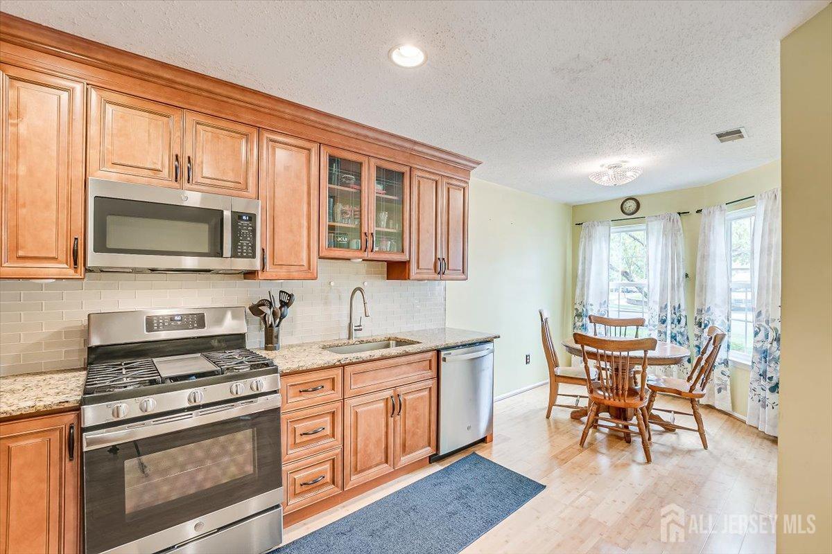 230 Nebula Road Piscataway, NJ 08854 - Photo 9 of 33 a kitchen with stainless steel appliances granite countertop a stove top oven a sink dishwasher a dining table and chairs with wooden floor