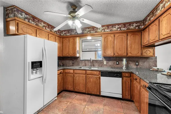 a kitchen with stainless steel appliances granite countertop a sink a stove and refrigerator