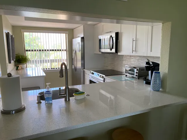 a kitchen with kitchen island a counter top space a sink a stove and a window