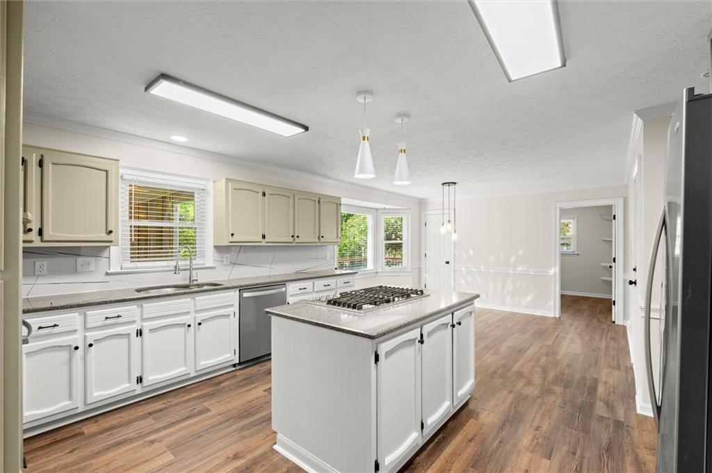 4922 Signal Court Southwest Lilburn, GA 30047 - Photo 11 of 49 a kitchen with stainless steel appliances granite countertop a stove top oven a sink dishwasher and white cabinets with wooden floor