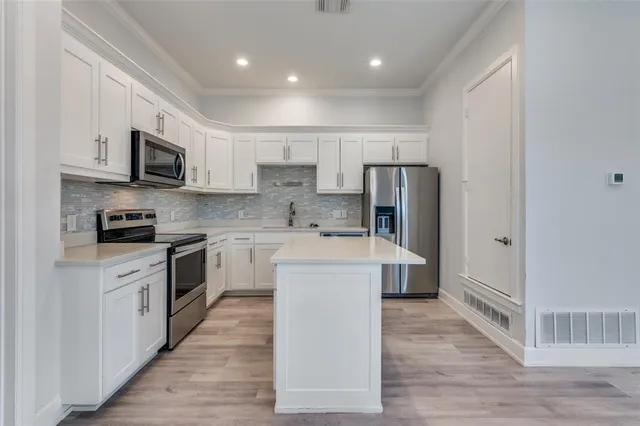 a kitchen with stainless steel appliances granite countertop a refrigerator a stove top oven a sink and dishwasher with wooden floor