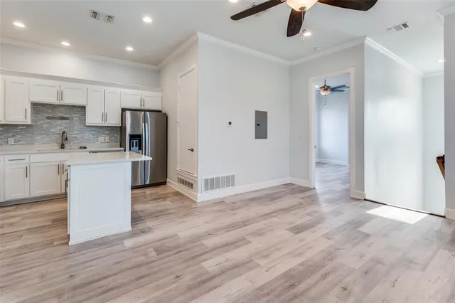 an empty room with wooden floor a ceiling fan and windows