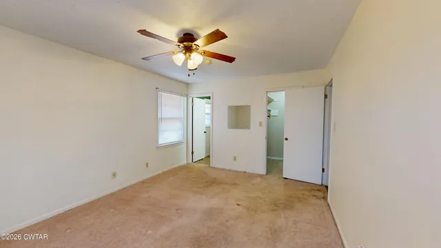 a view of an empty room and chandelier fan