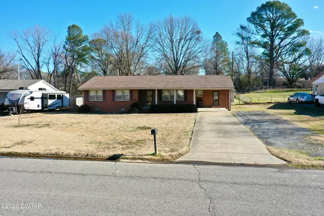 a view of a white house with a big yard and large trees