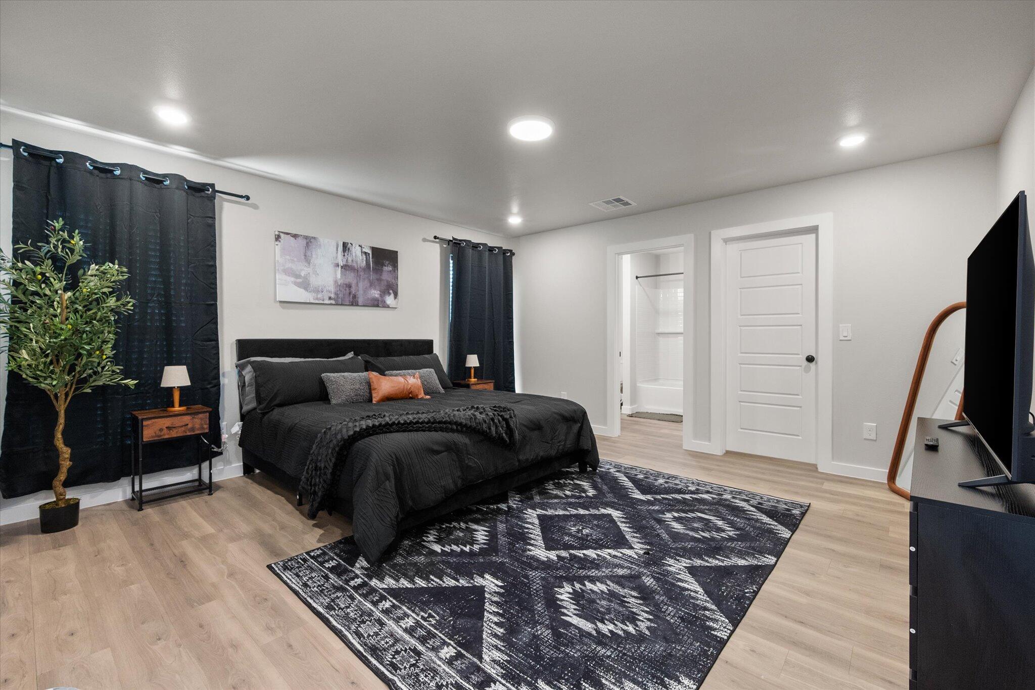 2146 Kokomo Avenue Lubbock, TX 79407 - Photo 5 of 10 a spacious bedroom with a bed a couch and a potted plant