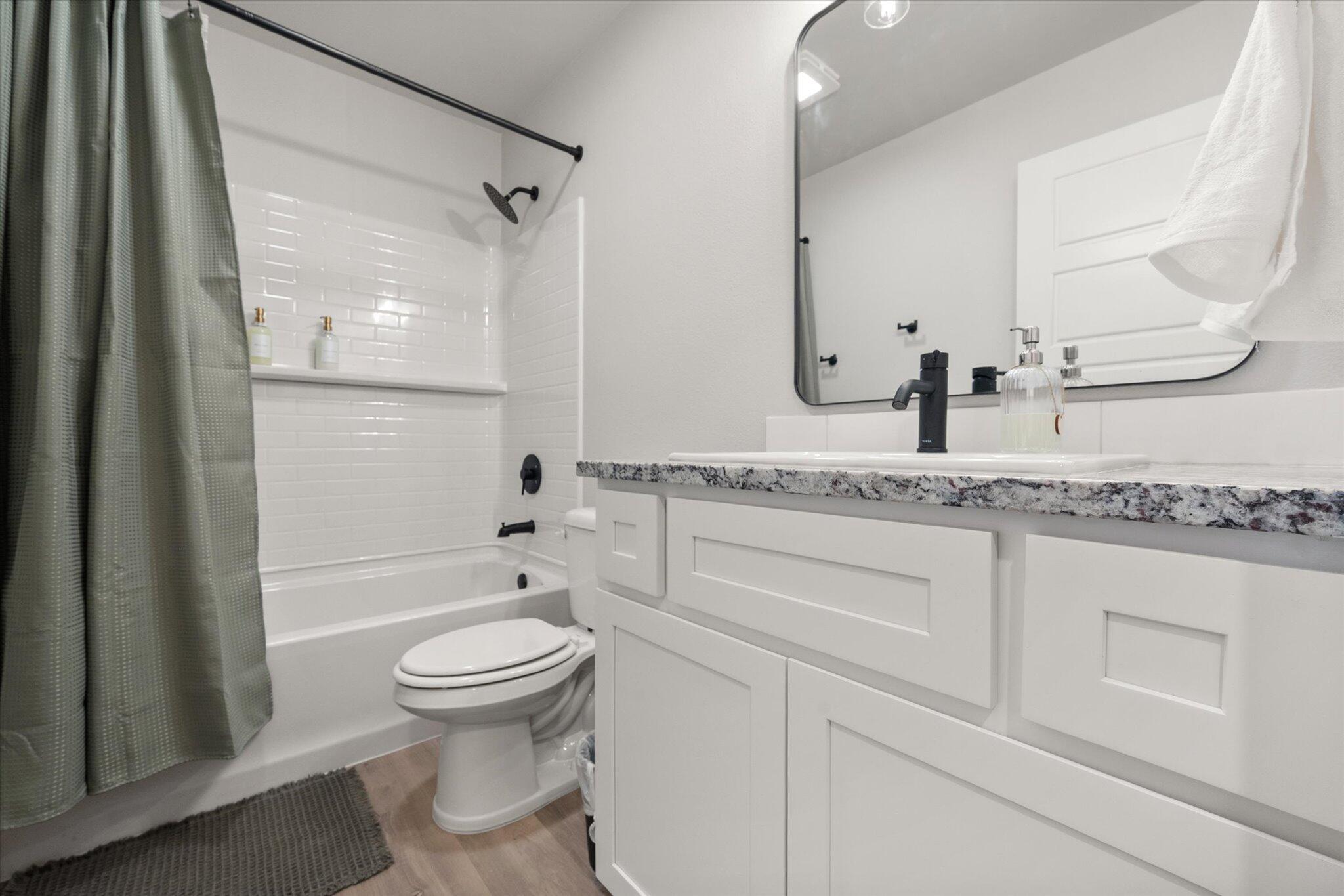2146 Kokomo Avenue Lubbock, TX 79407 - Photo 8 of 10 a bathroom with a granite countertop sink a toilet and a mirror