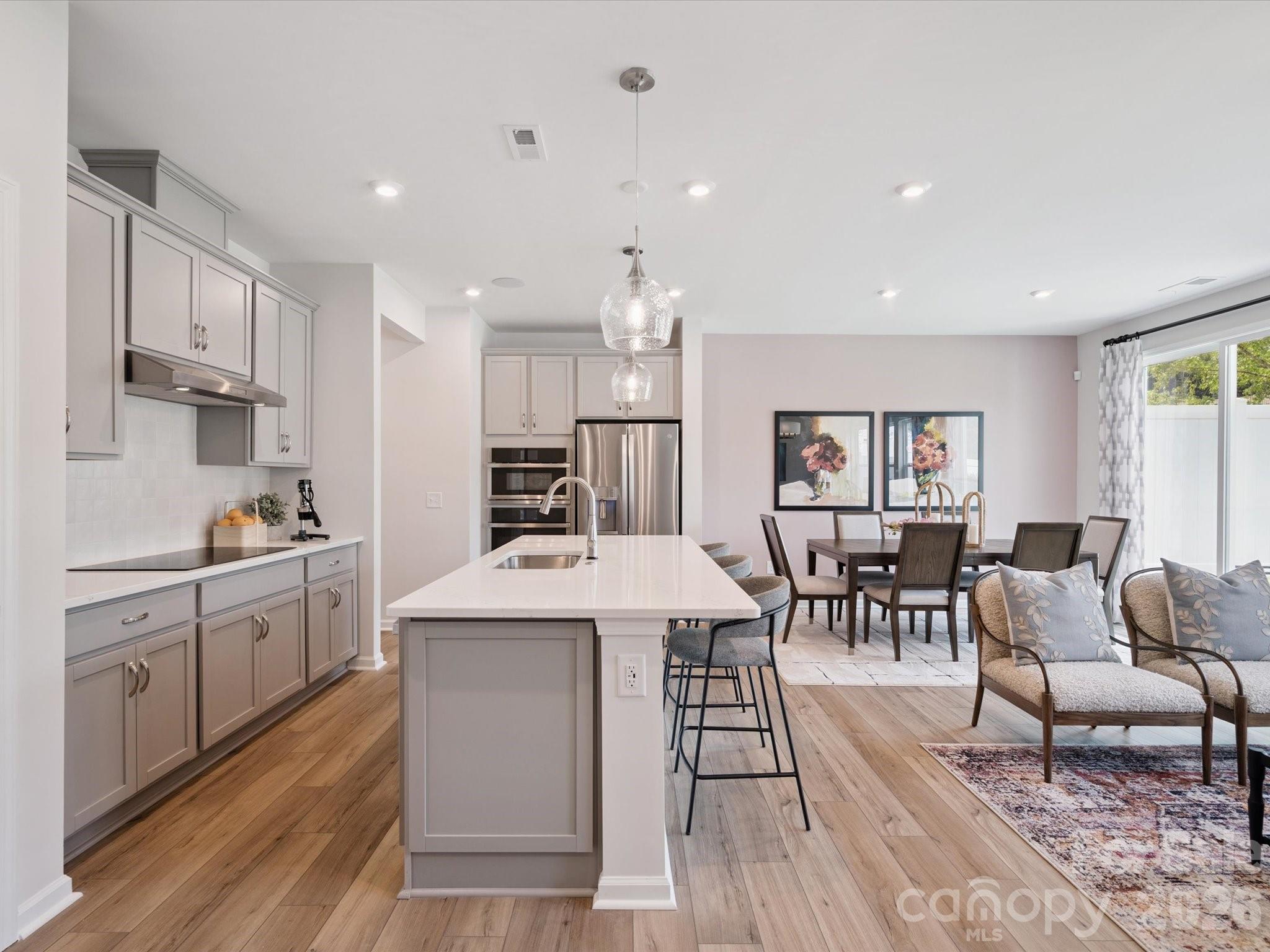 604 Webster Lane Cramerton, NC 28032 - Photo 5 of 20 a kitchen with stainless steel appliances kitchen island granite countertop a stove top oven a sink a dining table and chairs with wooden floor