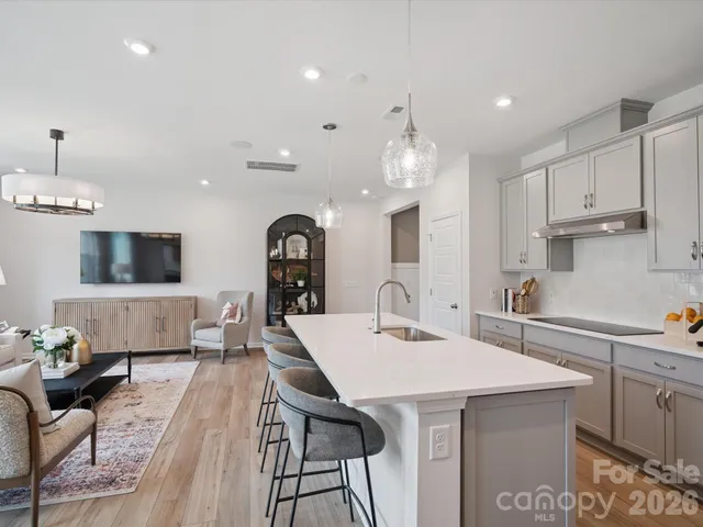 a living room with stainless steel appliances kitchen island granite countertop a large window and a view of kitchen