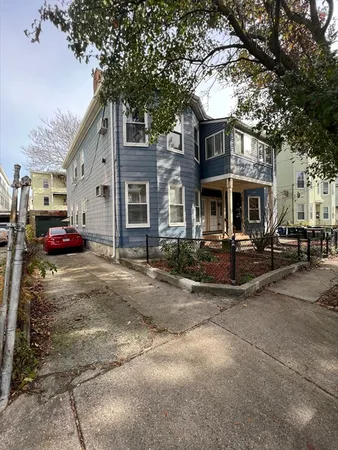a front view of a building with lot of cars and trees