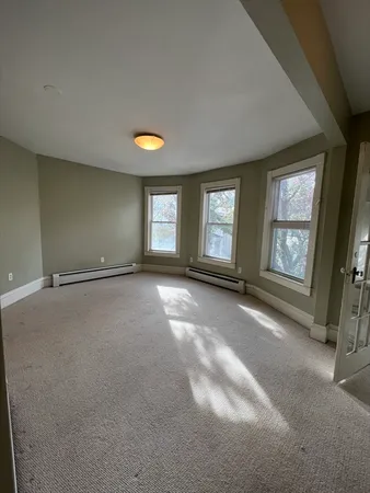 an empty room with windows and fireplace