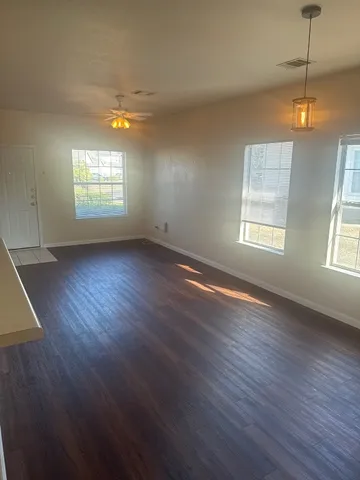 an empty room with wooden floor and windows