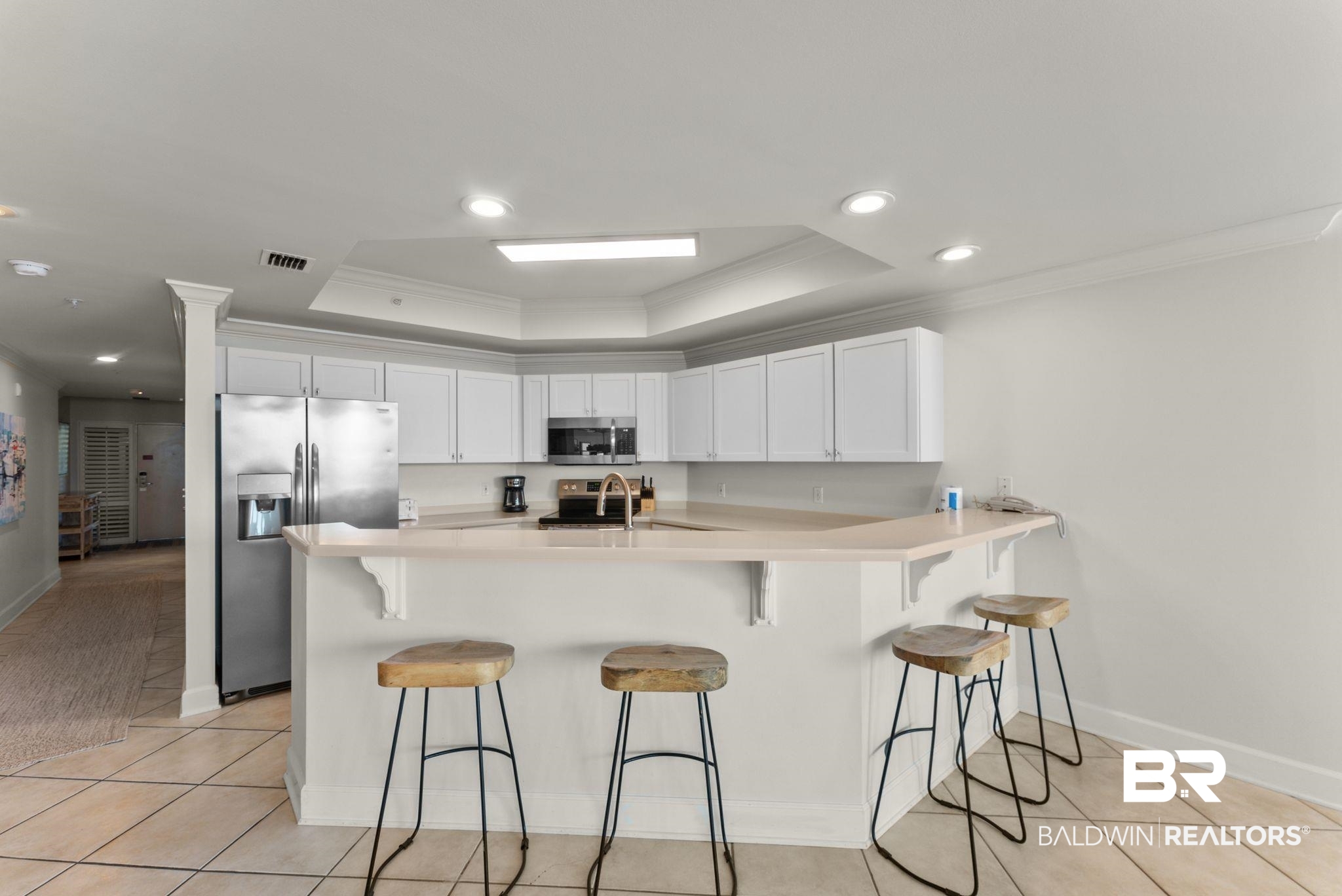 27580 Canal Road, Unit 1233 Orange Beach, AL 36561 - Photo 36 of 79 Kitchen with a peninsula, crown molding, a kitchen bar, light countertops, and a tray ceiling