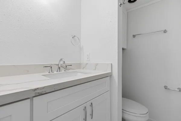a bathroom with a granite countertop toilet sink mirror and vanity