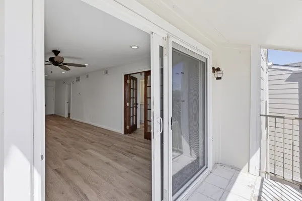 a view of a hallway with wooden floor and a bathroom