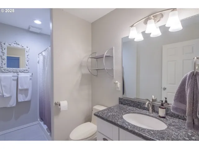 a bathroom with a granite countertop sink a toilet and a mirror