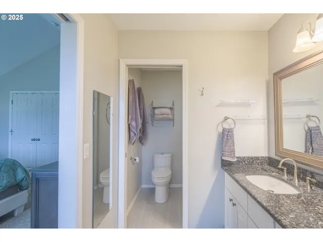 a bathroom with a granite countertop sink a toilet and a mirror