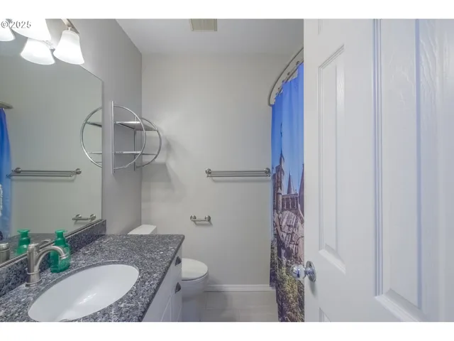 a bathroom with a granite countertop sink a toilet and shower