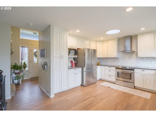 a kitchen with refrigerator a stove top oven a refrigerator with wooden floor