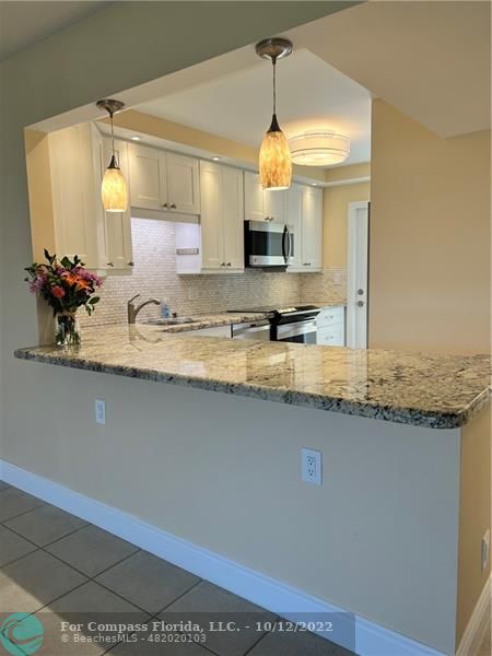 a kitchen with kitchen island granite countertop a sink a counter and cabinets