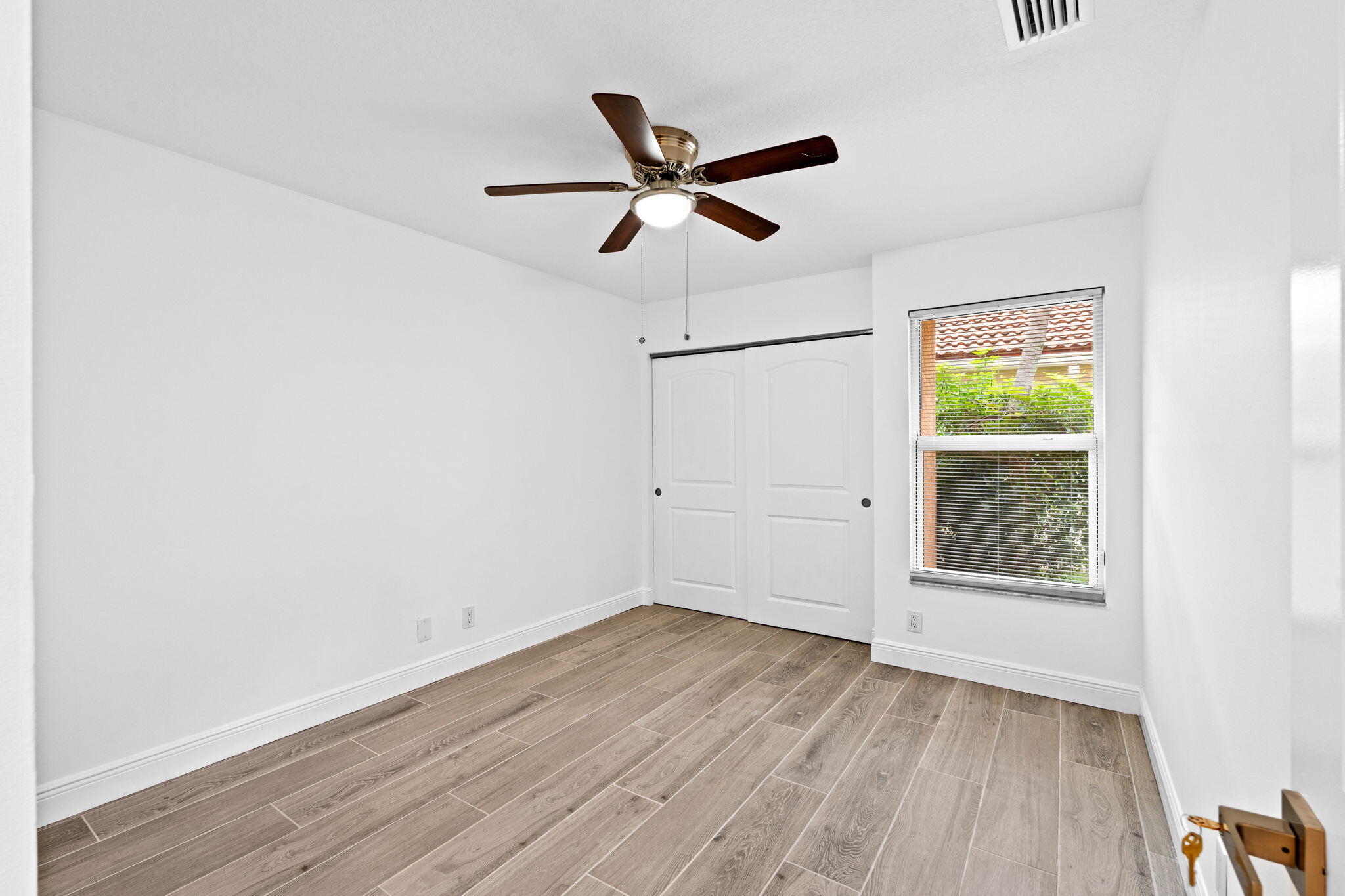5122 Elpine Way Riviera Beach, FL 33418 - Photo 20 of 35 a view of empty room with wooden floor and fan