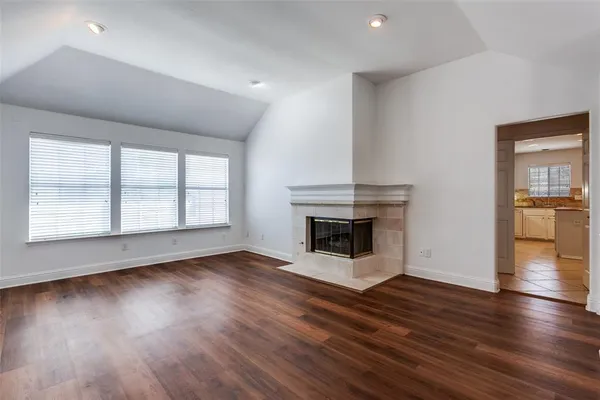 an empty room with wooden floor fireplace and windows