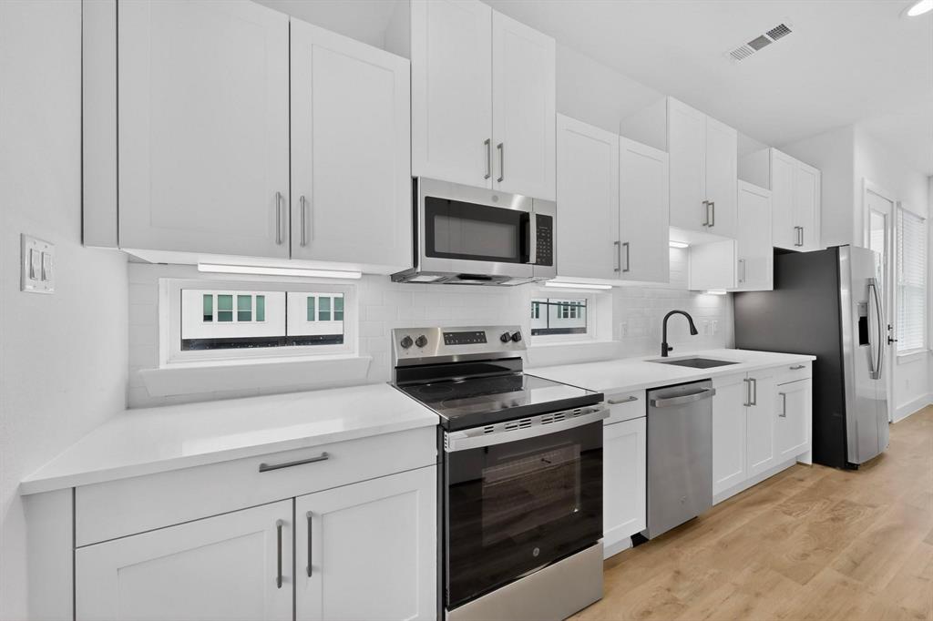 2226 Shea Road, Unit 103 Dallas, TX 75235 - Photo 8 of 35 Modern kitchen featuring white cabinetry, stainless steel appliances, white countertops, and wood-finish flooring