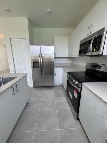 a kitchen with stainless steel appliances granite countertop a refrigerator a stove a sink and a microwave