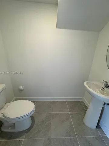 a white toilet sitting next to a white sink and vanity