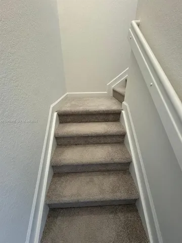 a view of staircase with white walls and empty racks