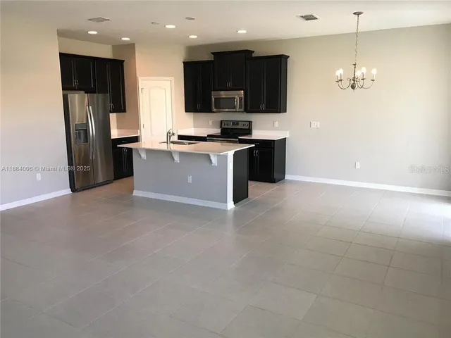 a large kitchen with stainless steel appliances granite countertop a refrigerator and a stove top oven