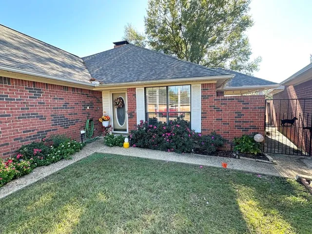 a view of a brick house with a yard potted plants and a table