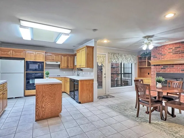 a kitchen with stainless steel appliances kitchen island granite countertop dining table chair and a refrigerator