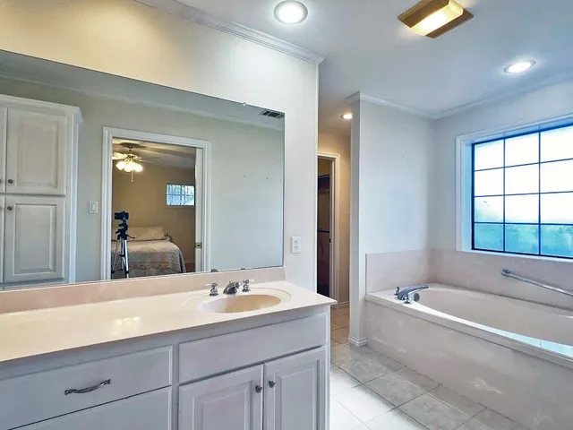a bathroom with a tub a sink and a window